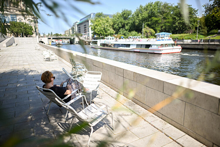 Woman sitting by the Spree reading