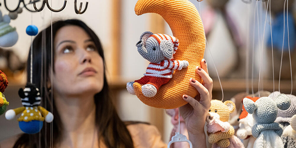 Eine Frau betrachtet eine gehäkelte Baby-Spieluhr