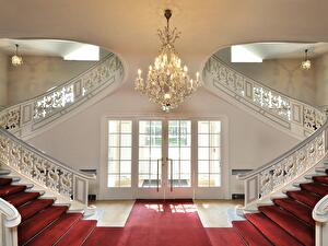 Prunkvolle doppelläufige Treppe im Schloss Schönhausen mit rotem Teppich, Kronleuchter und Glastüren.