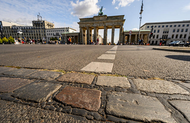 An der Stelle, wo zu DDR-Zeiten die Berliner Mauer stand, sind vor dem Brandenburger Tor Pflastersteine, die an die Mauerzeiten errinern.