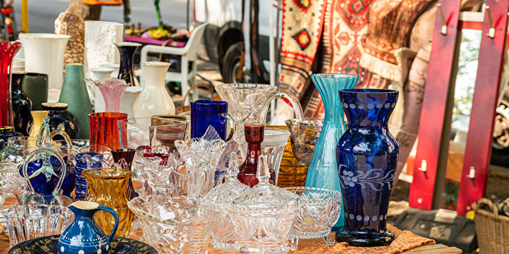 Glaswaren und andere Trödelobjekte aus Glas stehen auf dem Flohmarkttisch.