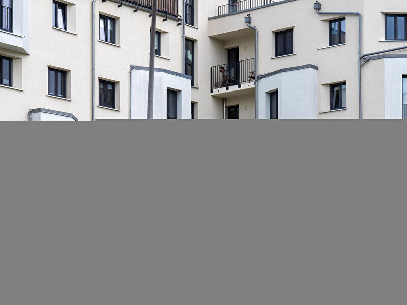 Mehrgeschossiges Wohngebäude mit Balkonen, Fenstern und heller Fassade an einer Straßenecke