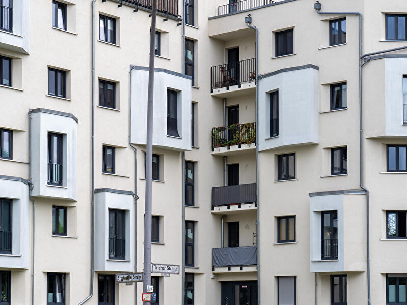 Mehrgeschossiges Wohngebäude mit Balkonen, Fenstern und heller Fassade an einer Straßenecke