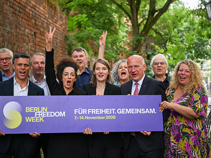 Teilnehmende einer Demokratieinitiative präsentieren in Berlin ein Schild mit der Aufschrift „Für Freiheit. Gemeinsam.“ und werben für die Berlin Freedom Week 2026.
