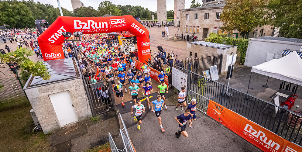 Teilnehmende des B2Run Berlin laufen am Olympiastadion durch ein Tor