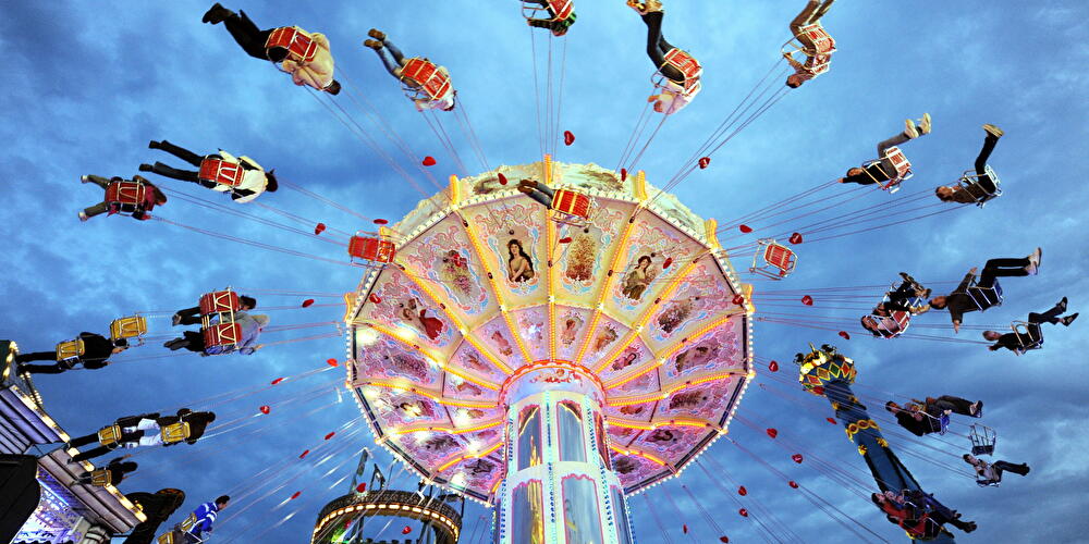 A colorfully lit chain carousel spins at a fairground.