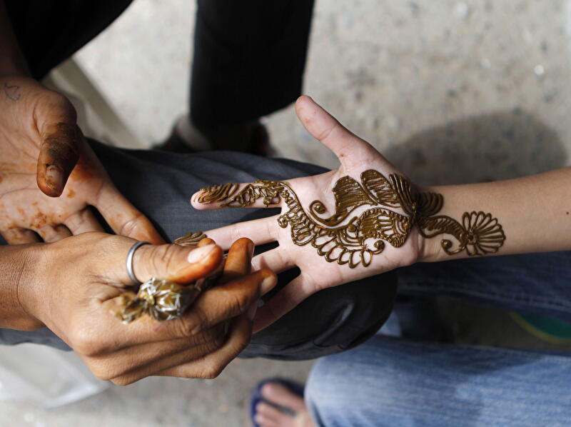 A person is getting a floral tattoo on their hand.