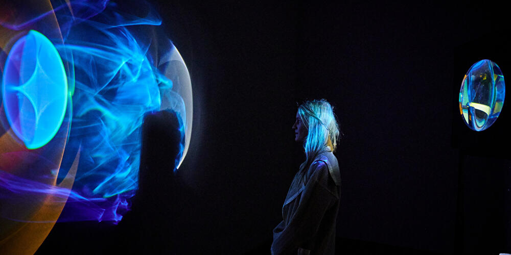 Eine Besucherin betrachtet eine Lichtinstallation  in der Galerie Neugerriemschneider in Berlin.
