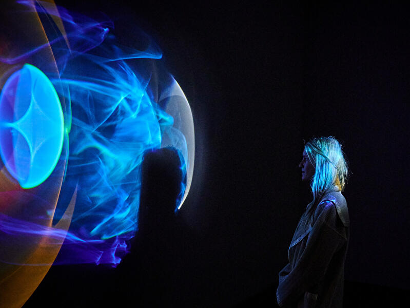 Eine Besucherin betrachtet eine Lichtinstallation  in der Galerie Neugerriemschneider in Berlin.