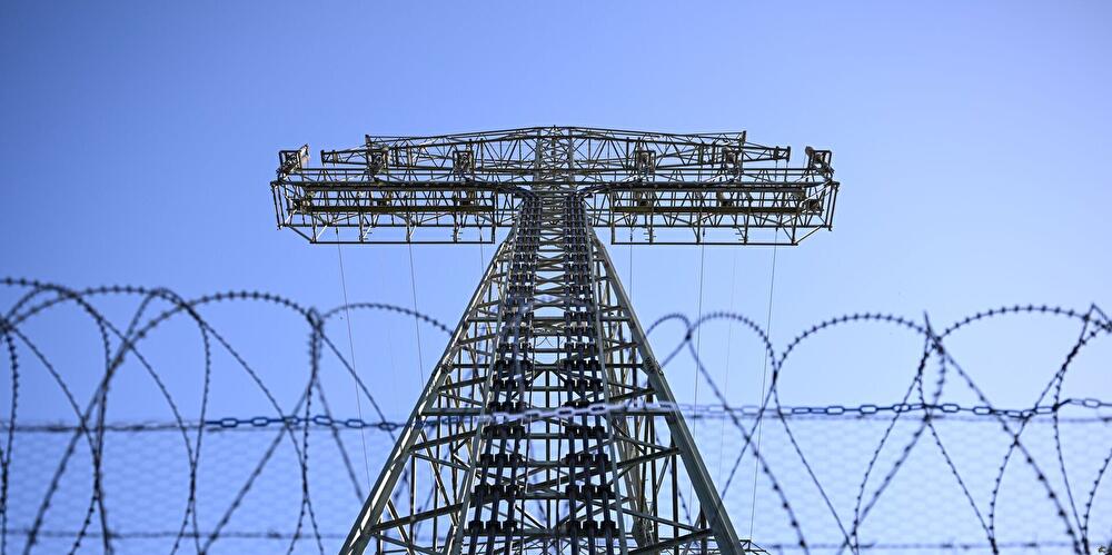 Verstärkter Sicherheitszaun mit Stacheldraht vor einem Strommast, der nach einem Brandanschlag im September 2025 zusätzlich gesichert wurde.