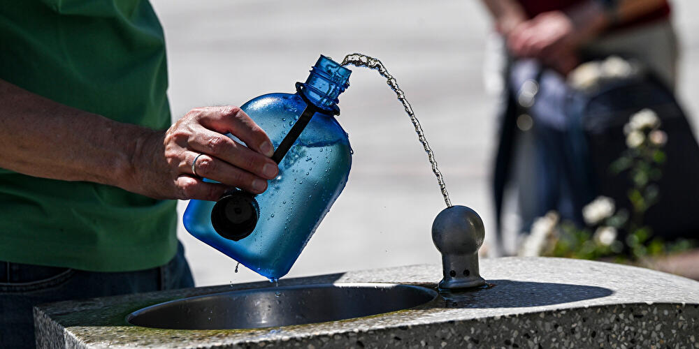 Ein Mann nutzt einen Wasserspender, um seine Trinkflasche aufzufüllen.