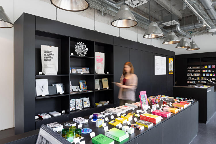 Museumsshop mit Designbüchern, Produkten und Auslage in modernem Ausstellungsraum.