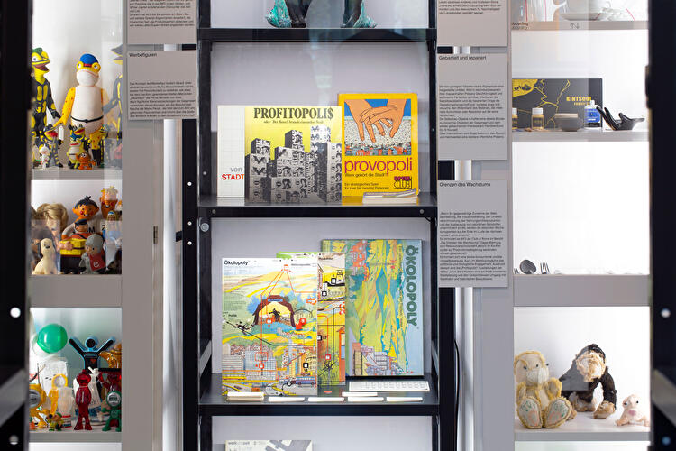 Detailansicht einer Vitrine mit Spielen, Figuren und Objekten zu Konsum und Wachstum.