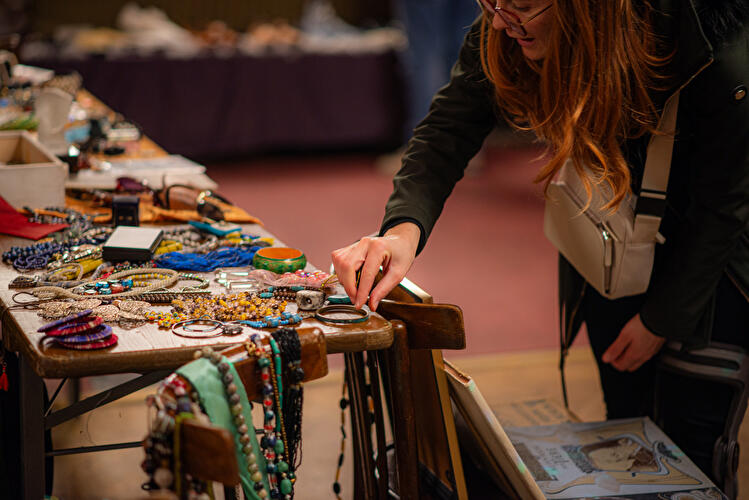 Person betrachtet Schmuck und Accessoires auf einem Verkaufsstand mit Ketten, Armbändern und weiteren Secondhand-Artikeln.