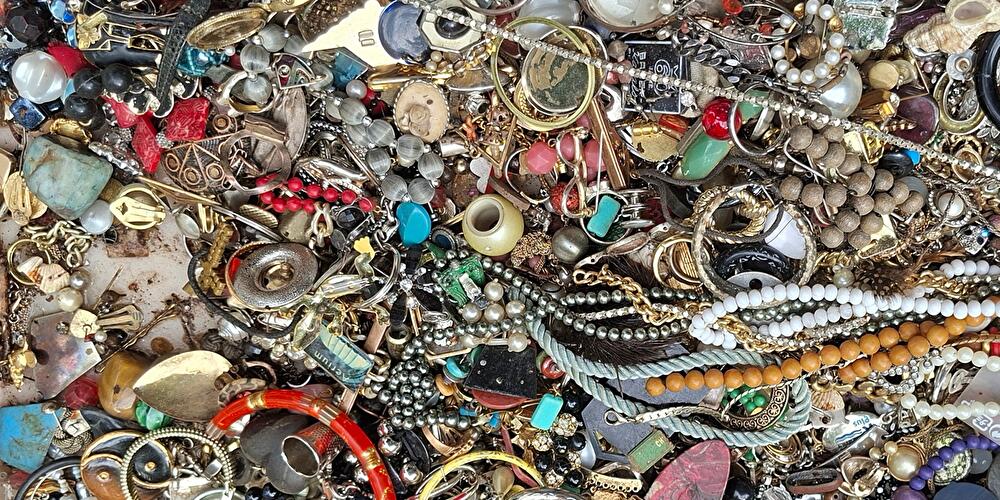 Ketten, Ohrringe, Armreifen und anderer alter Mode-Schmuck liegen auf einem Tisch.