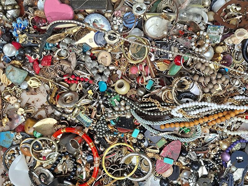 Ketten, Ohrringe, Armreifen und anderer alter Mode-Schmuck liegen auf einem Tisch.