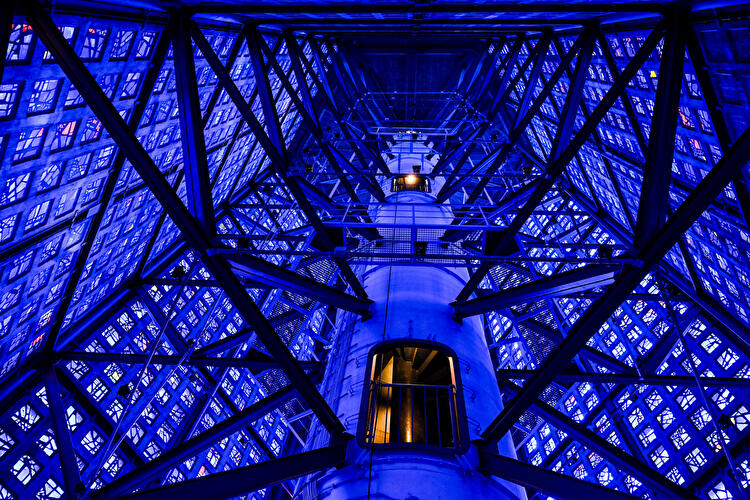Blick nach oben in den Glockenturm der Kaiser-Wilhelm-Gedächtniskirche mit zentralem Turmschacht, Stahlträgern und blau verglasten Innenwänden.