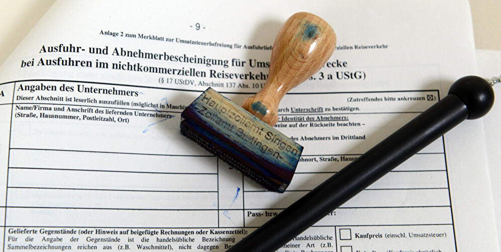 Ein Formular, ein Stempel und ein Kugelschreiber des Zollamtes liegen auf dem Tisch.