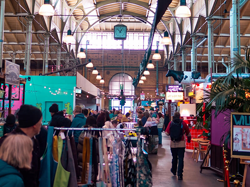 Designmarkt in der Arminiusmarkthalle mit Besucher:innen, Marktständen und historischer Hallenarchitektur.
