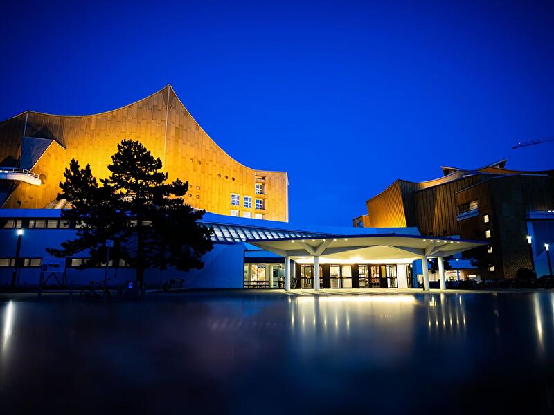 Berliner Philharmonie mit beleuchteter Fassade vor tiefblauem Abendhimmel.