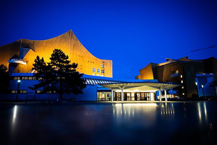 Berliner Philharmonie mit beleuchteter Fassade vor tiefblauem Abendhimmel.