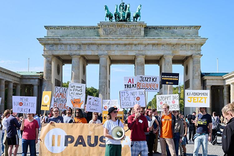 Demonstration vor dem Brandenburger Tor mit Plakaten zur Regulierung von Künstlicher Intelligenz.