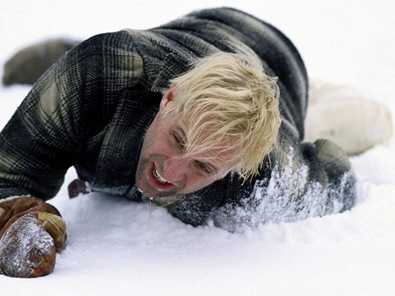 Person in Winterkleidung kriecht durch tiefen Schnee und greift mit Handschuh nach vorn.