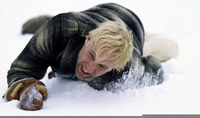 Person in Winterkleidung kriecht durch tiefen Schnee und greift mit Handschuh nach vorn.