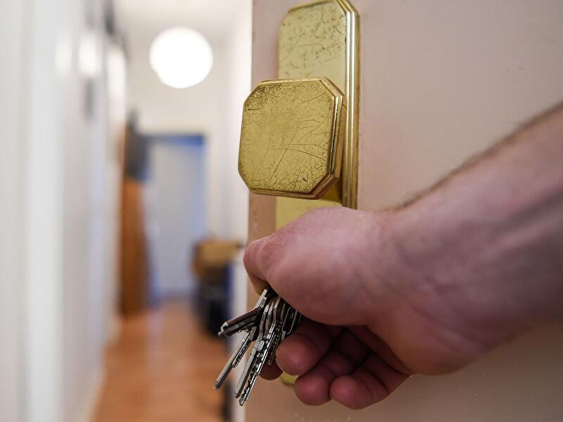 Hand öffnet Wohnungstür mit Schlüsselbund im Türschloss.