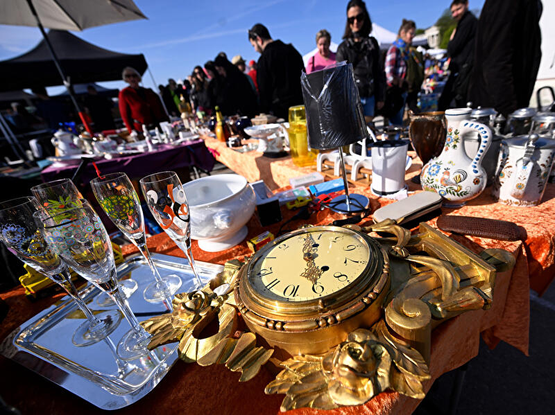 Eine alte Uhr, Sektgläser, Vasen und Tassen werden auf einem Flohmarkt angeboten.