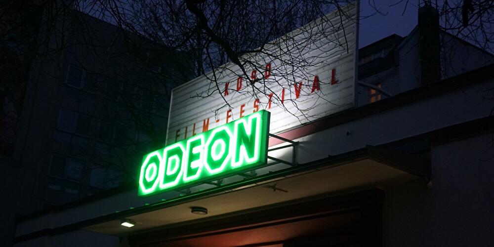 Beleuchteter Eingang des Filmtheaters Odeon bei Abenddämmerung während des Koso Filmfestivals.