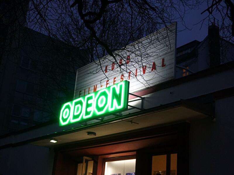 Beleuchteter Eingang des Filmtheaters Odeon bei Abenddämmerung während des Koso Filmfestivals.