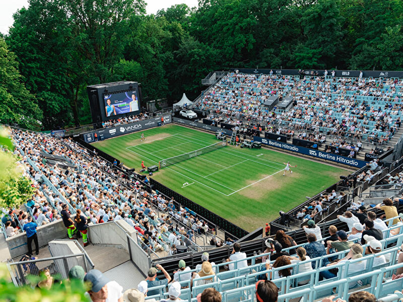 Zuschauer:innen verfolgen ein Match auf dem Rasenplatz der Berlin Tennis Open aus der Vogelperspektive.