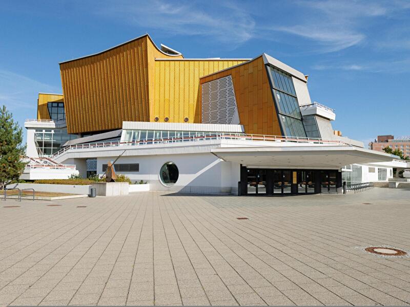 Berliner Philharmonie mit goldfarbener Fassade und markanter Architektur vor einem freiem Platz.