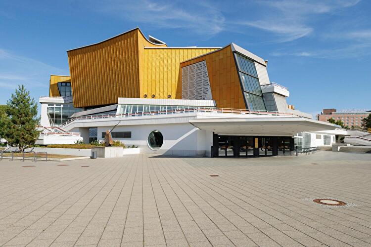 Berliner Philharmonie mit goldfarbener Fassade und markanter Architektur vor einem freiem Platz.