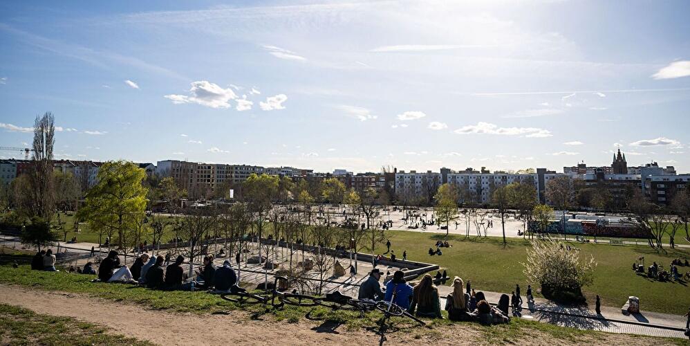 Menschen entspannen auf einer Wiese im Mauerpark an einem sonnigen Tag.