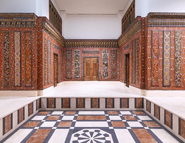 Historischer Raum mit reich verzierten Holzvertäfelungen und geometrisch gemustertem Steinboden im Pergamonmuseum.