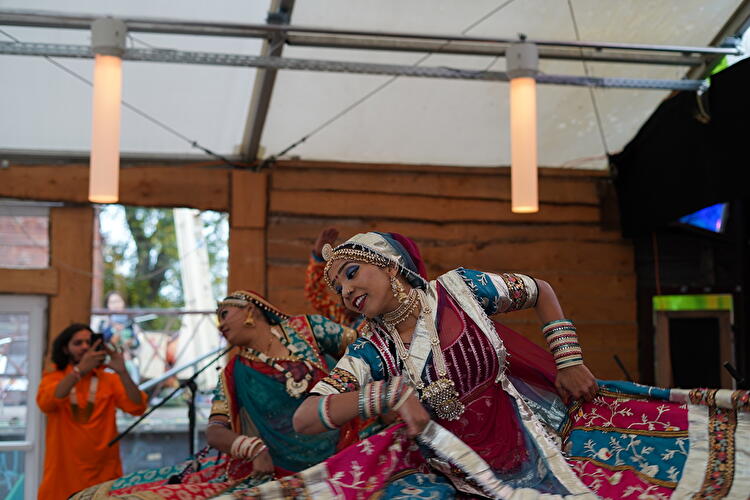 Zwei Tänzerinnen in farbenprächtigen traditionellen Gewändern führen beim Diwali-Fest in Berlin einen Tanz auf einer Bühne auf. Schmuck, bestickte Stoffe und fließende Bewegungen prägen die Szene.