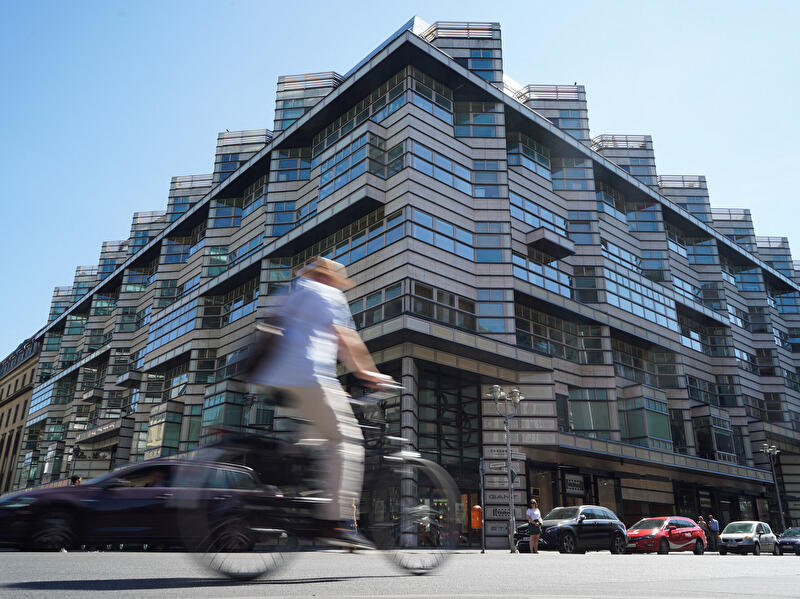 Quartier 205 an der Friedrichstraße mit gestufter Glasfassade und vorbeifahrendem Radfahrer.