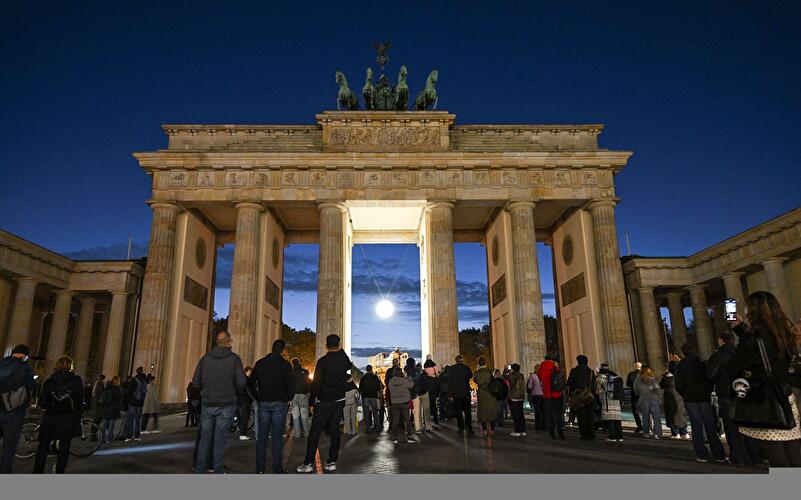 Menschen betrachten eine leuchtende Kugel unter dem Brandenburger Tor.