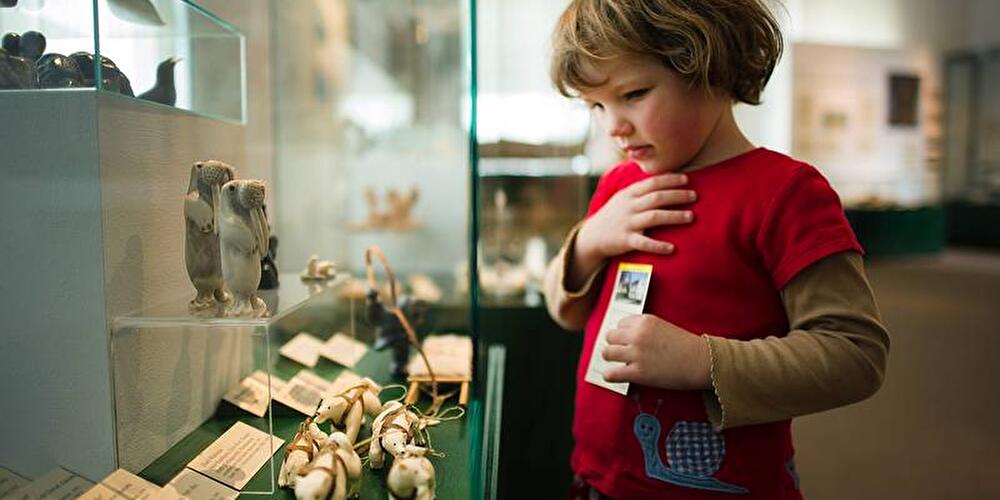Mädchen schaut in eine Vitrine im Museum