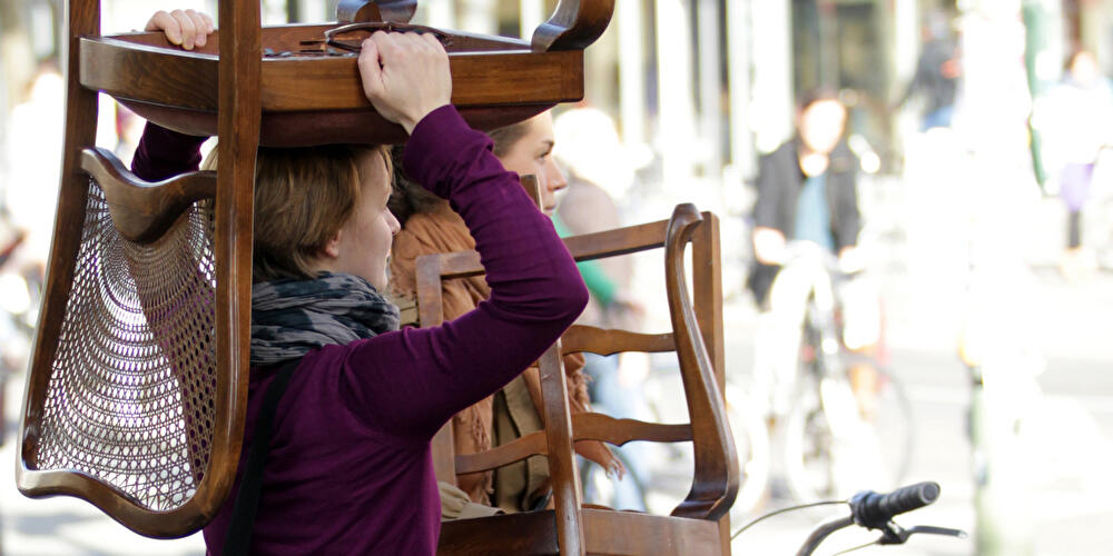 Zwei Frauen tragen alte Stühle vom Flohmarkt