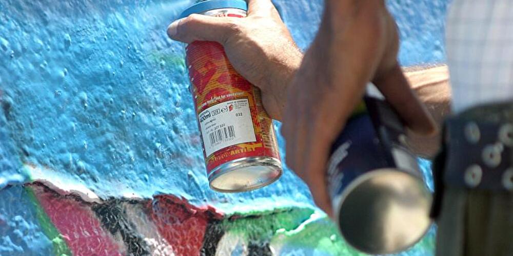 Ein Graffiti-Sprayer besprüht eine Mauer