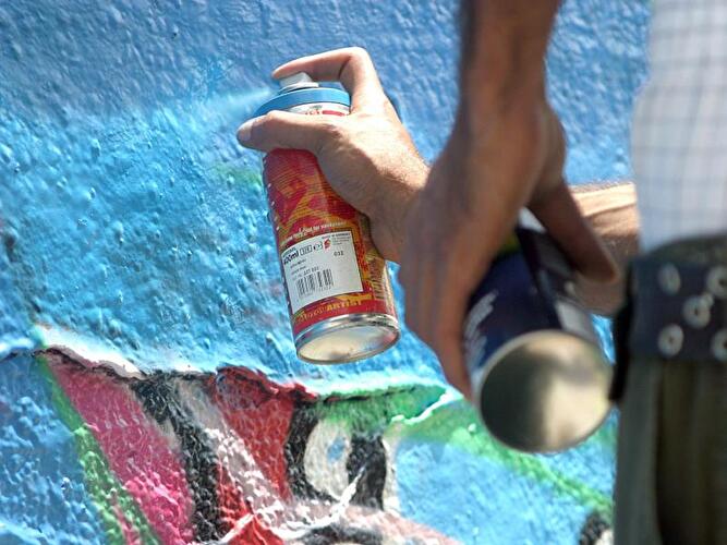 Ein Graffiti-Sprayer besprüht eine Mauer