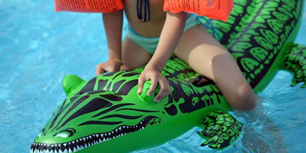 Kind schwimmt auf Plastikkrokodil