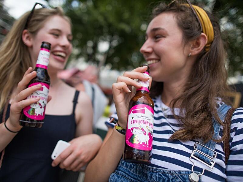 Touristinnen trinken Einhornbier aus Flaschen