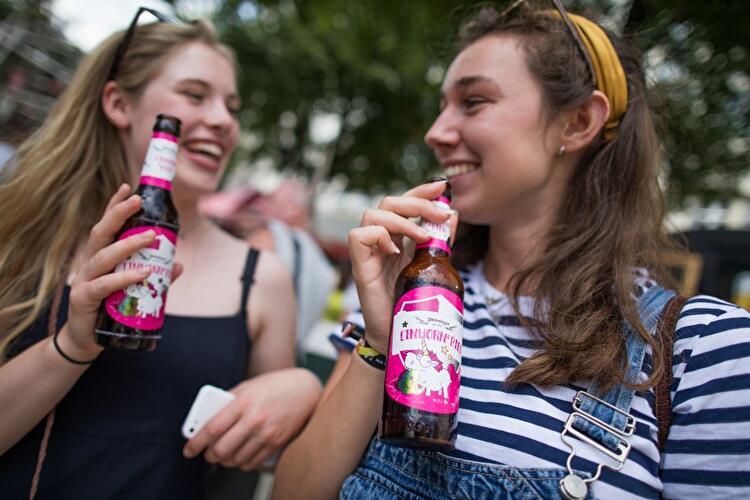 Touristinnen trinken Einhornbier aus Flaschen