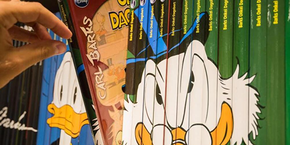 Mann nimmt Comicbuch über Dagobert Duck aus Regal