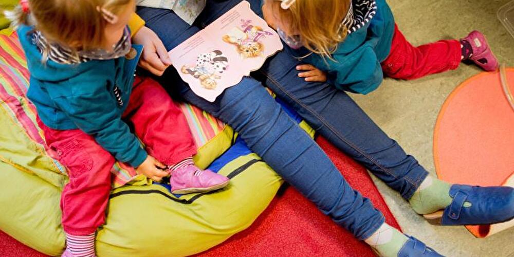 Frau liest mit zwei Kindern ein Buch