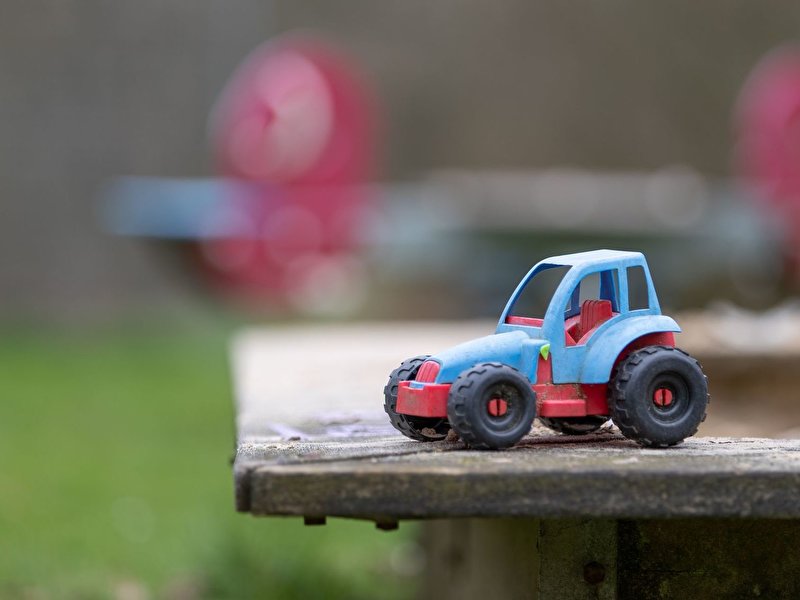 Ein Spielzeugauto steht auf dem Sandkasten von einem Spielplatz
